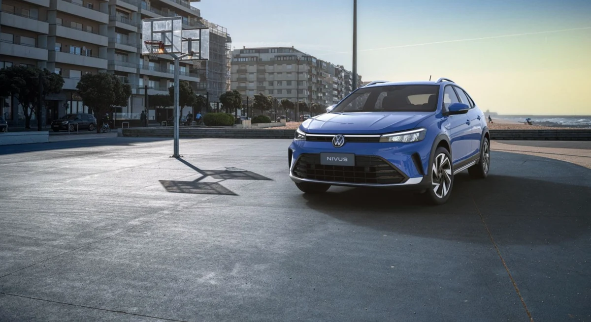 Volkswagen Nivus azul parado em área urbana à beira-mar, visto em três quartos dianteiro