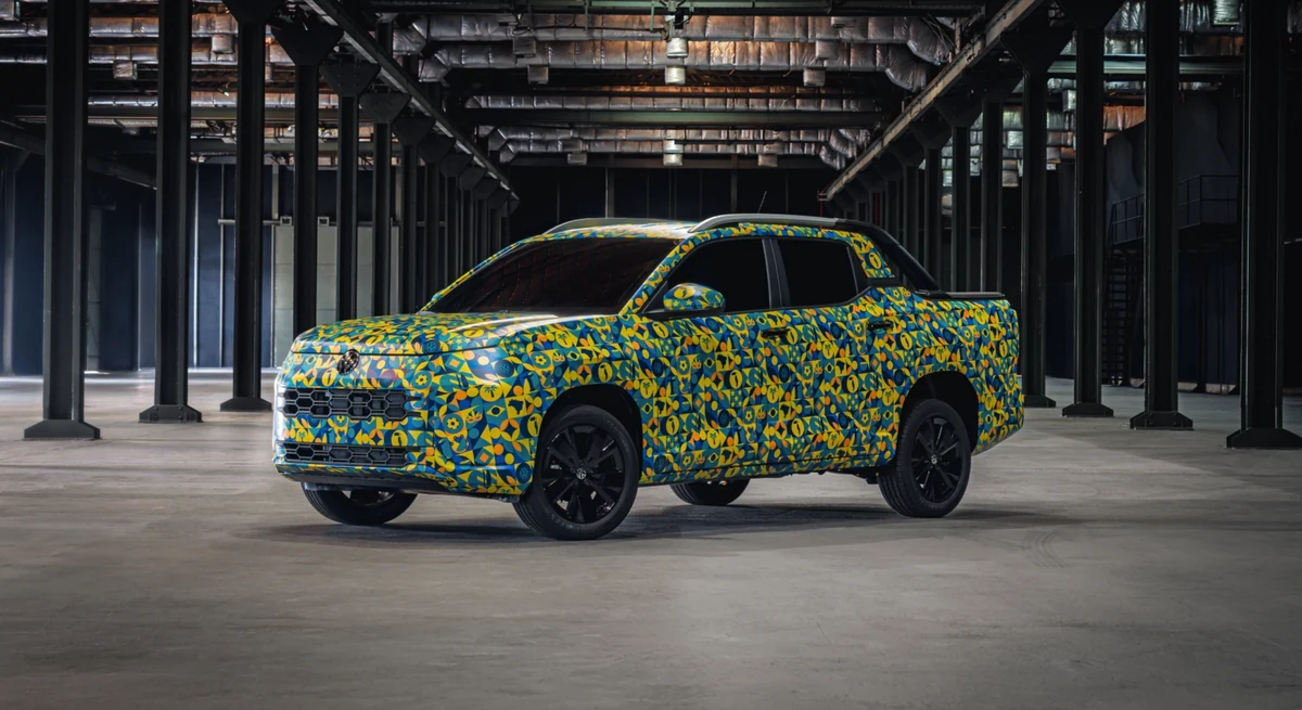 Protótipo da picape Volkswagen Tukan coberto pela camuflagem artística azul e amarela, visto de frente em um galpão industrial